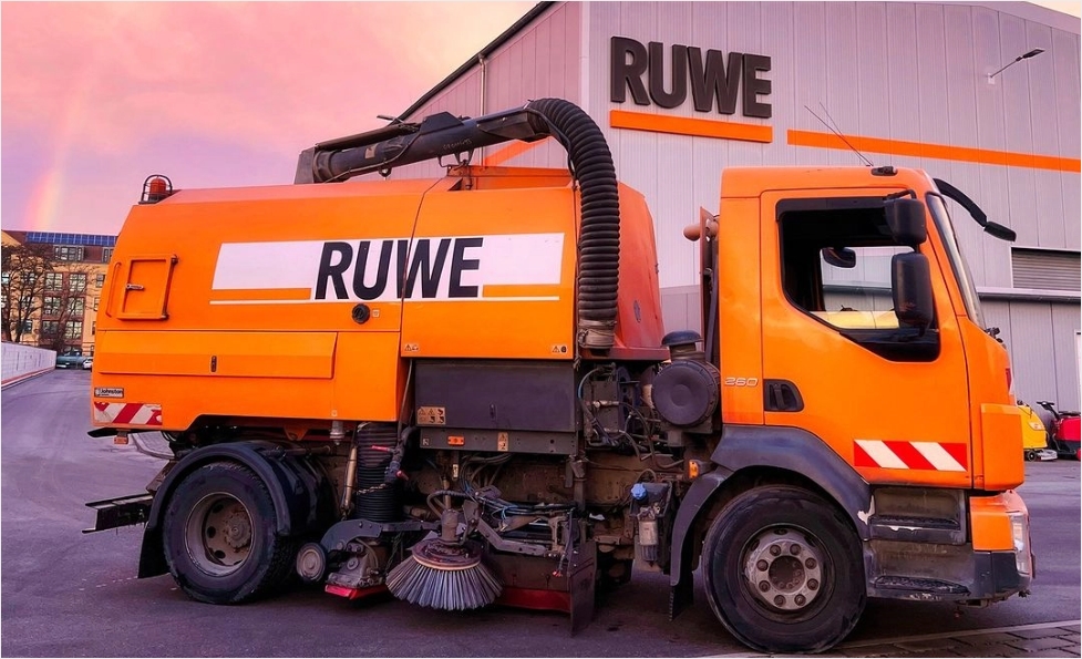 Ein großer orangefarbener Lastwagen parkt vor einem Gebäude.